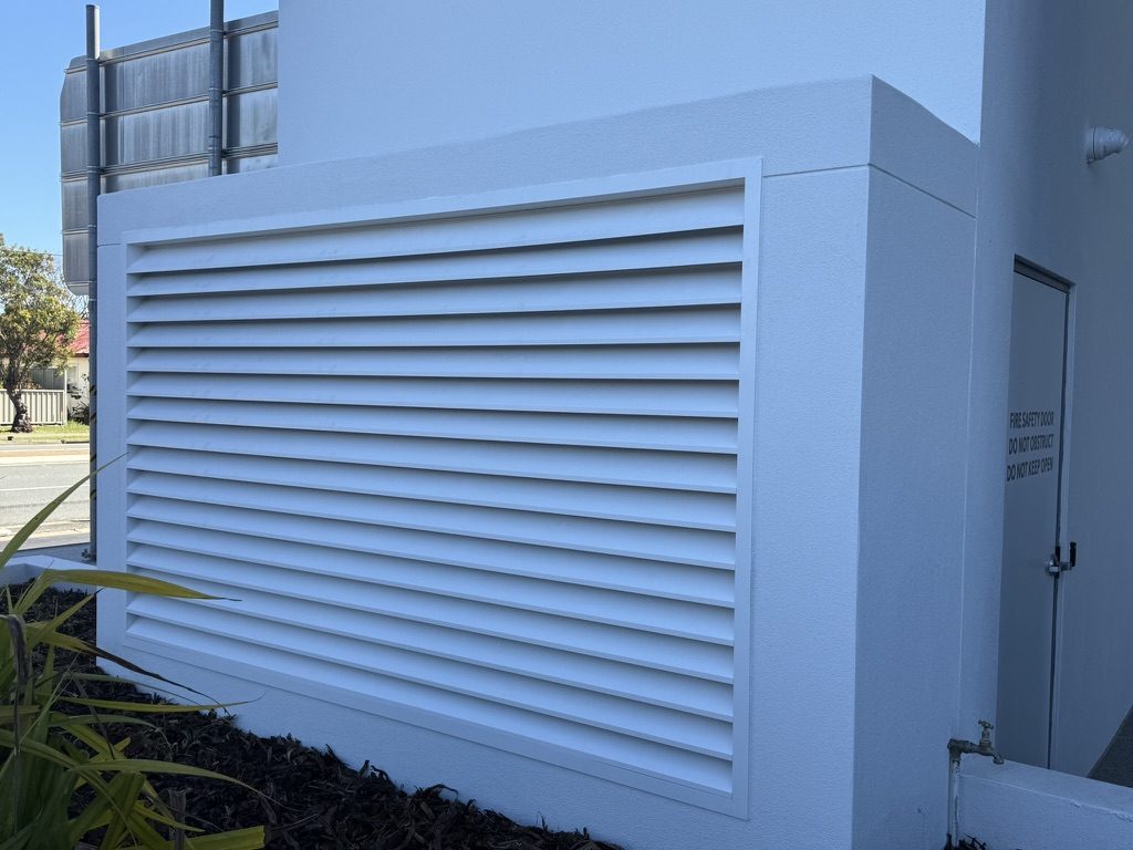 White powder-coated aluminium louvre plant screen to a commercial building