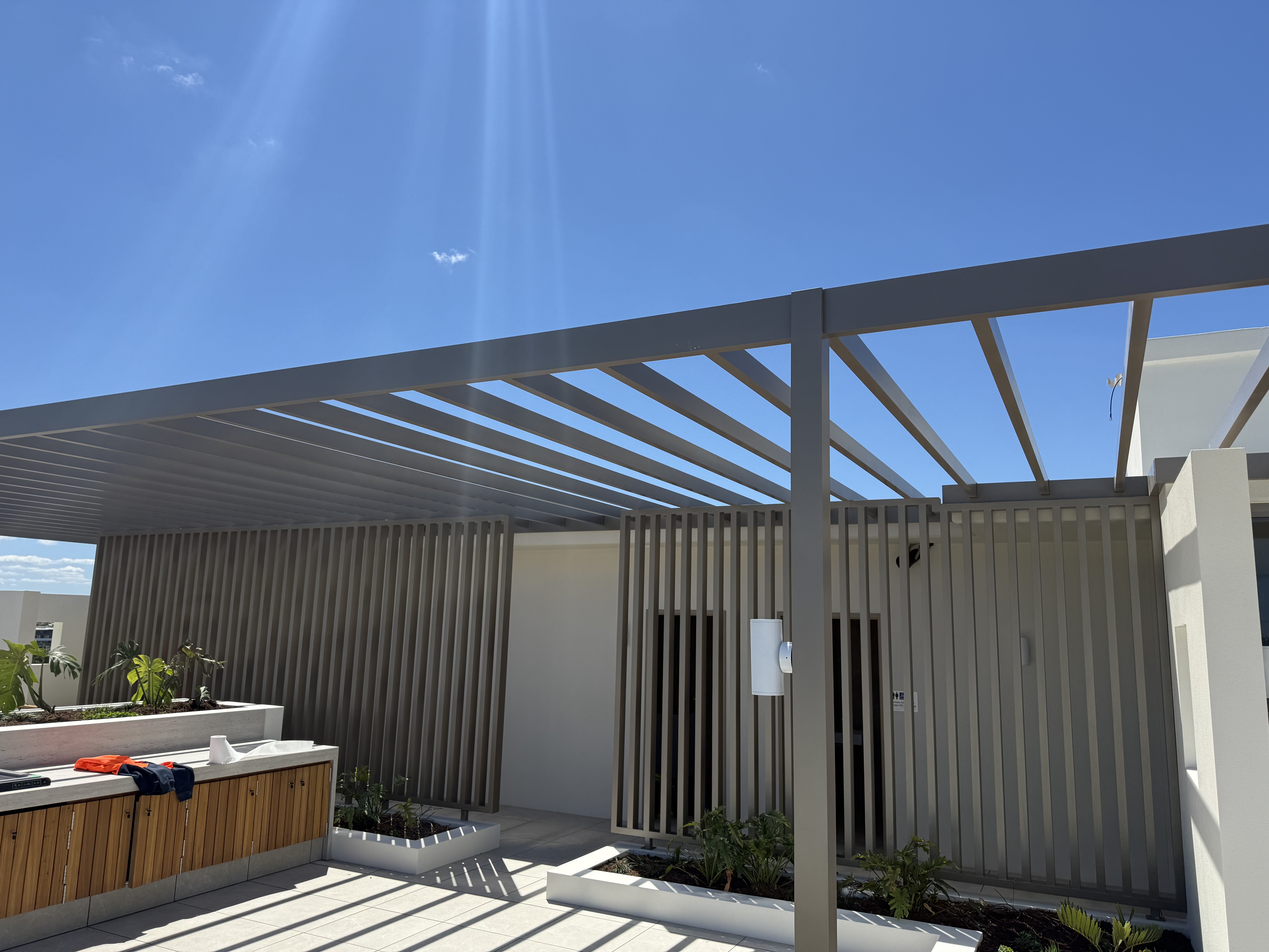 Aluminium slatted pergola and vertical batten screening to a rooftop communal terrace