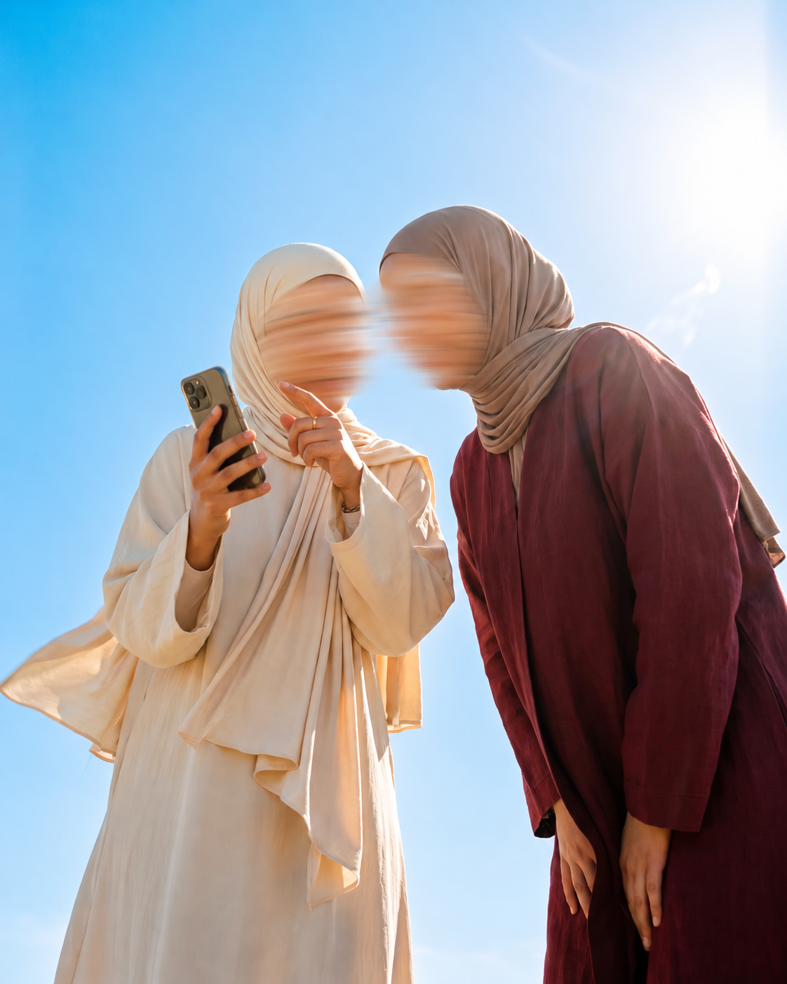 Twee vrouwen met een telefoon onder een blauwe lucht; gezichten onherkenbaar gemaakt