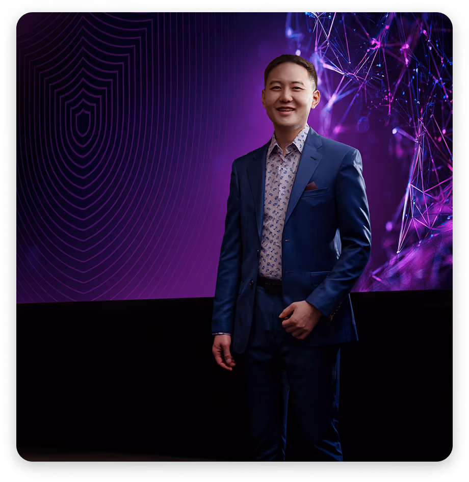 Smiling man in blue suit standing before a purple digital abstract background with network lines.