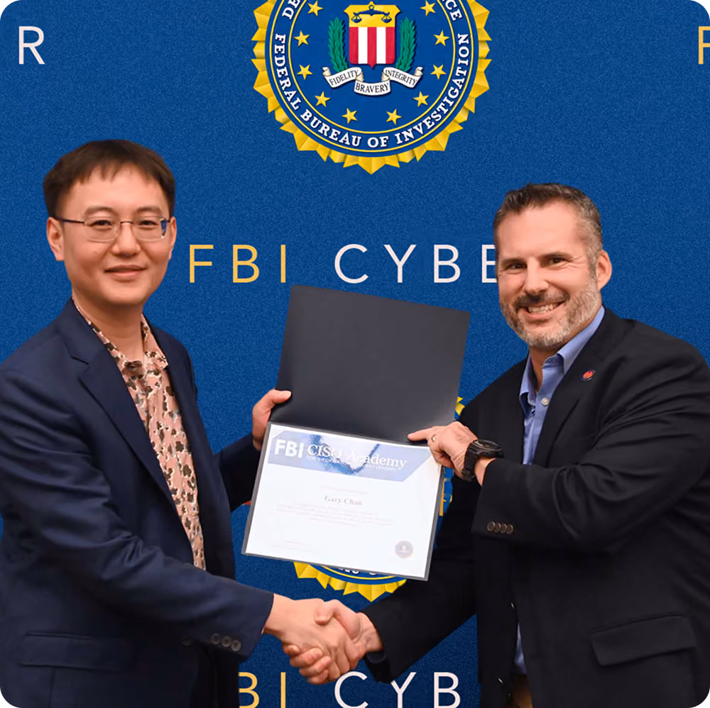 Two men shake hands while holding an FBI CISO Academy certificate against FBI Cyber backdrop.