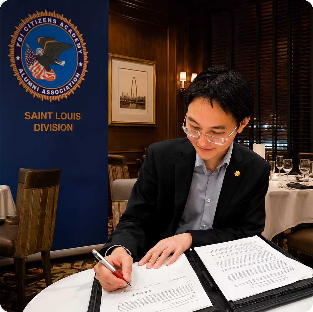 Gary signing documents at a table with FBI Citizens Academy Saint Louis Division banner nearby.