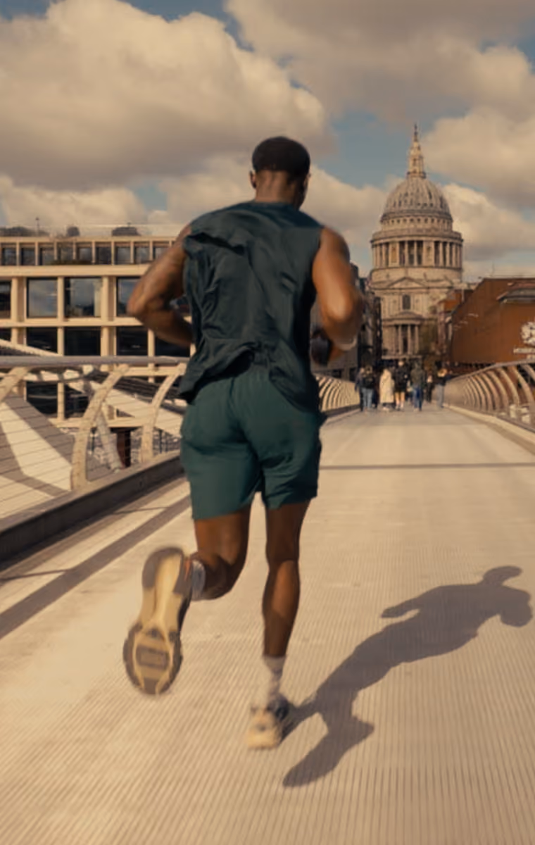 Person jogging on a bridge with St. Paul's Cathedral visible in the background on a partly cloudy day.
