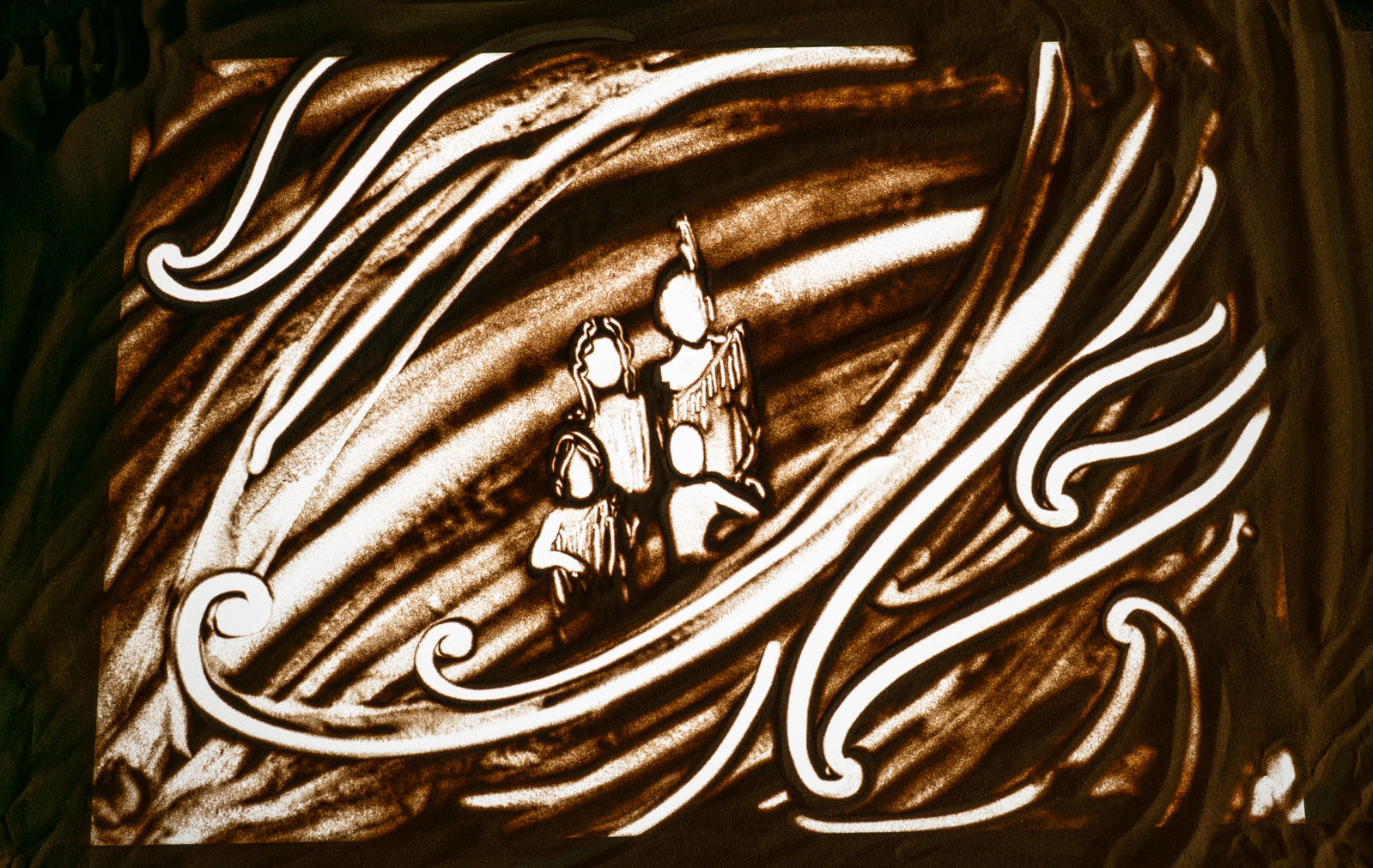 Sand art depicting four people surrounded by swirling water patterns.