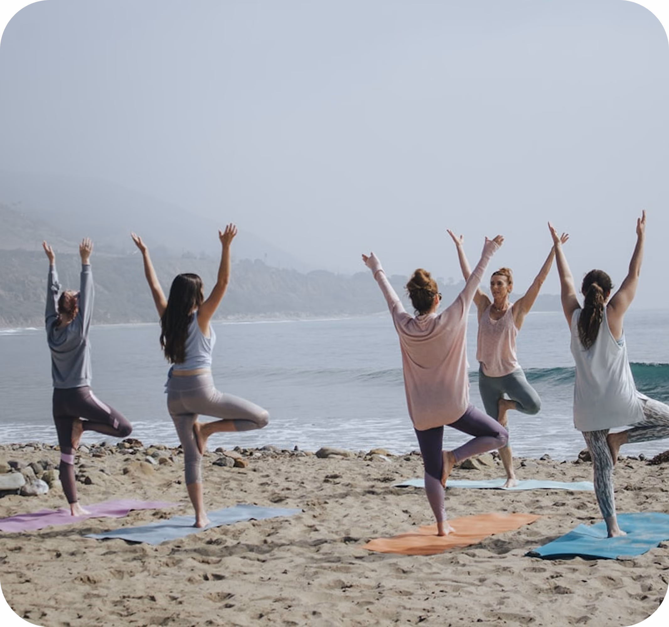 Students taking a yoga class on the beach