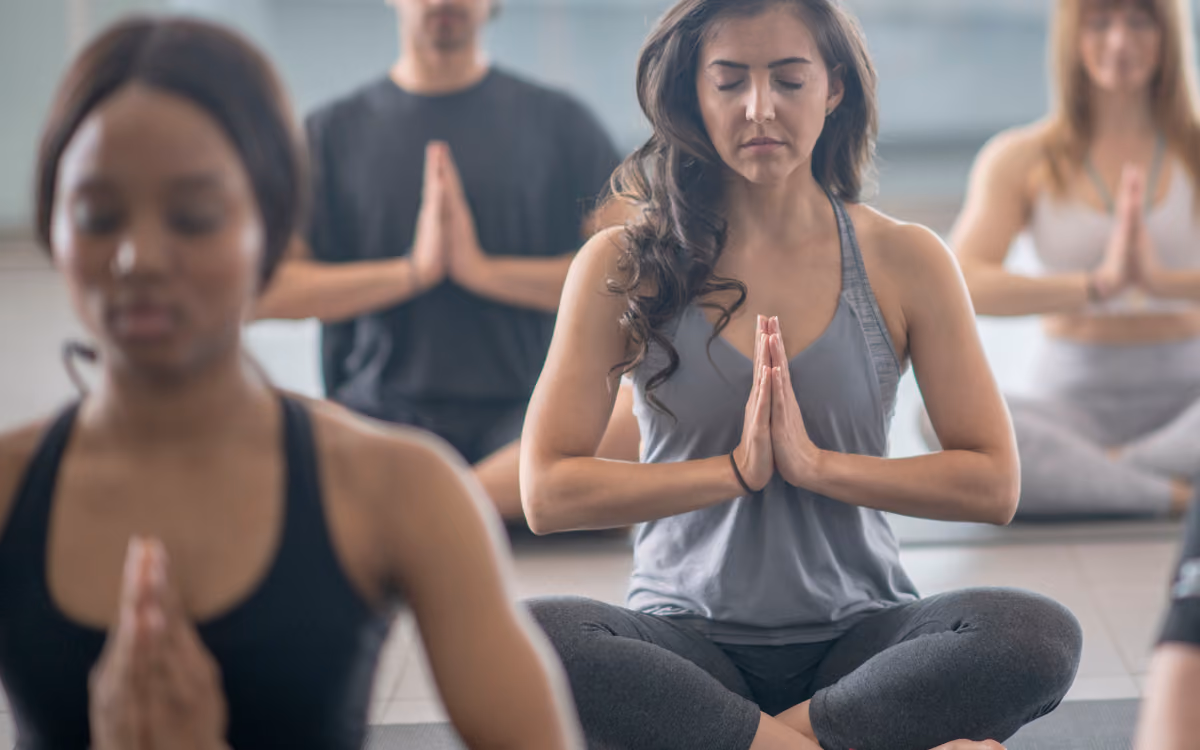 Students with hands at heart in yoga class