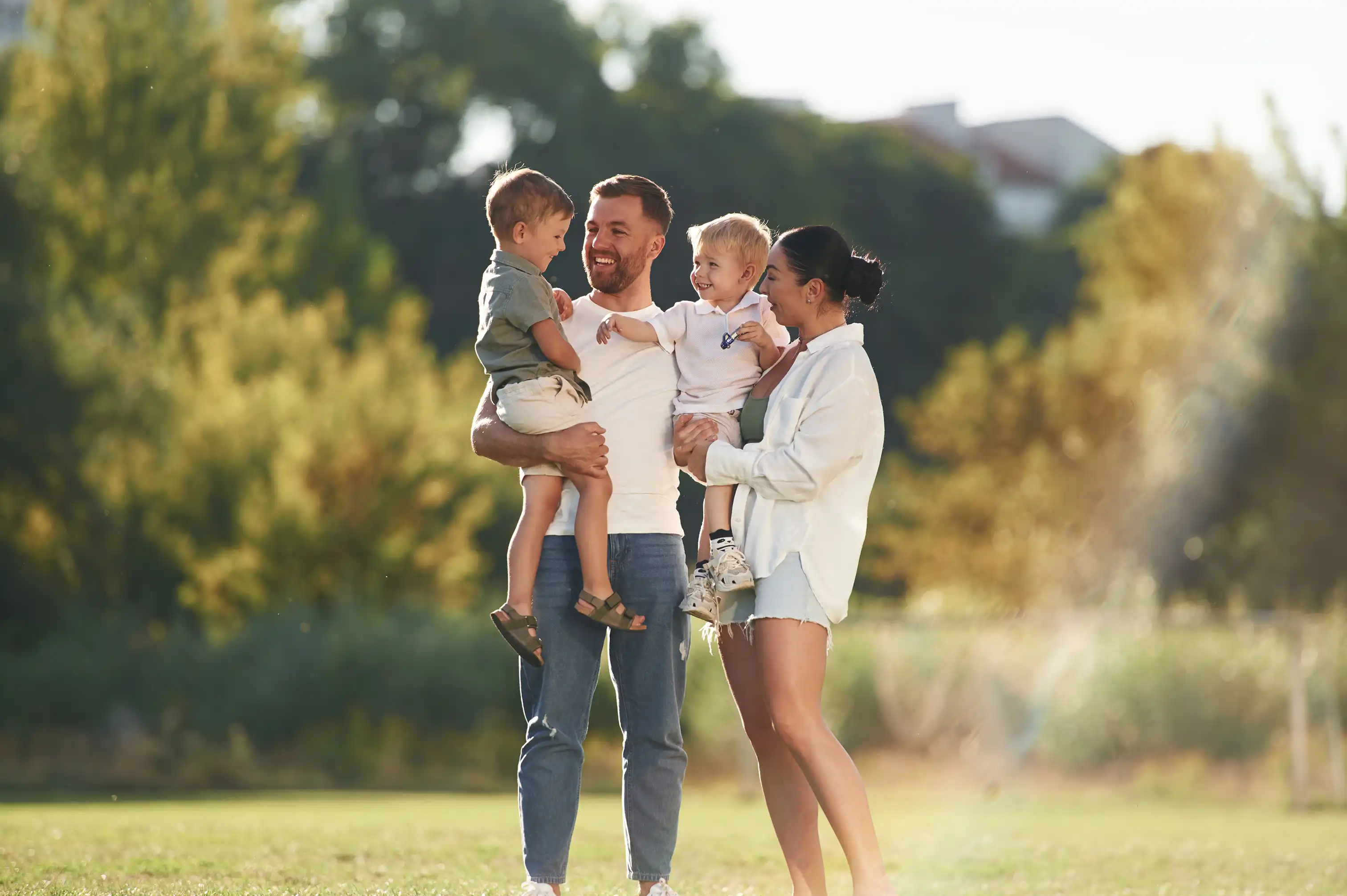 Young family together in a park with mum and dad holding a child each