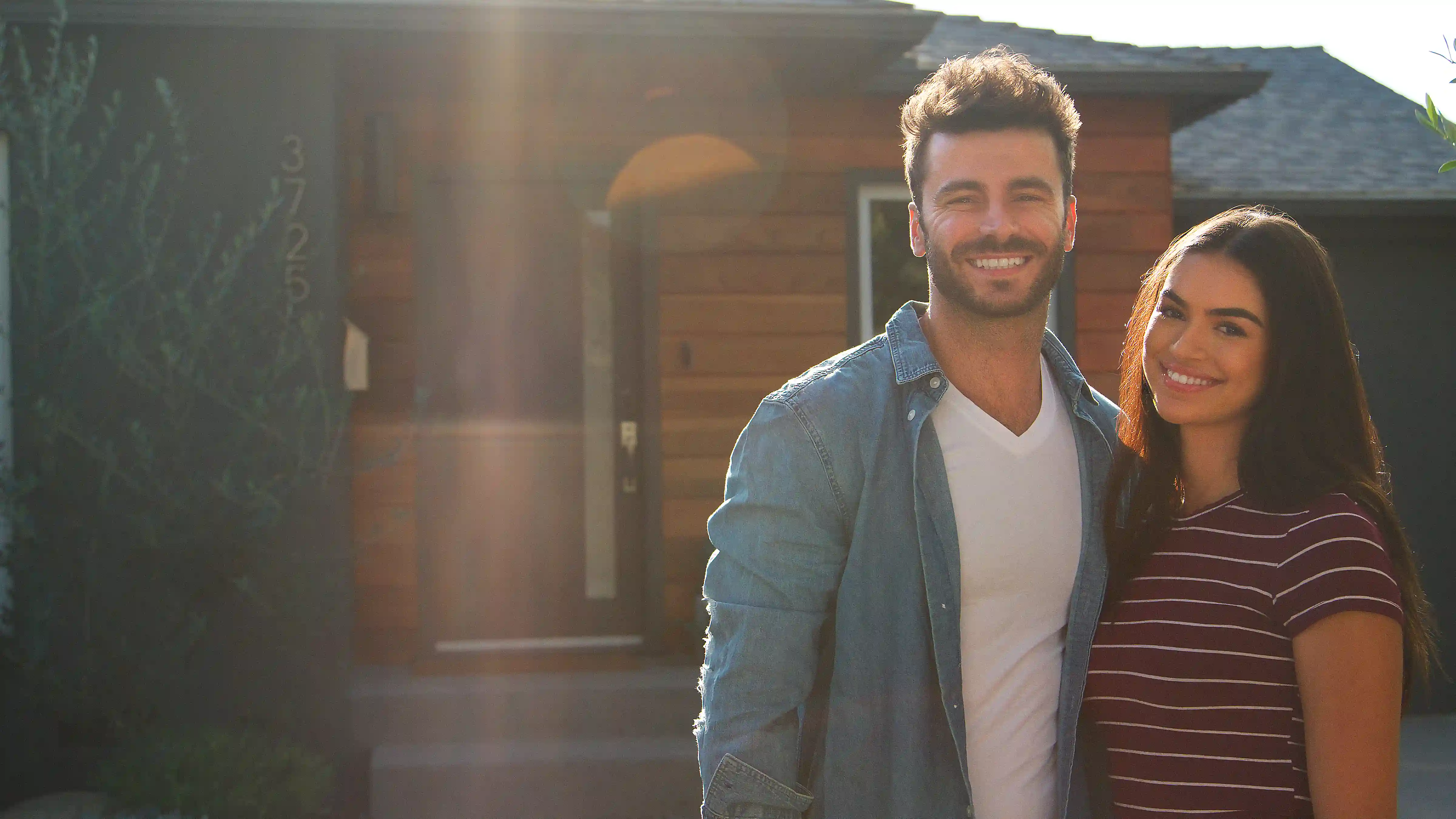 Young couple standing in front of their new home smiling.