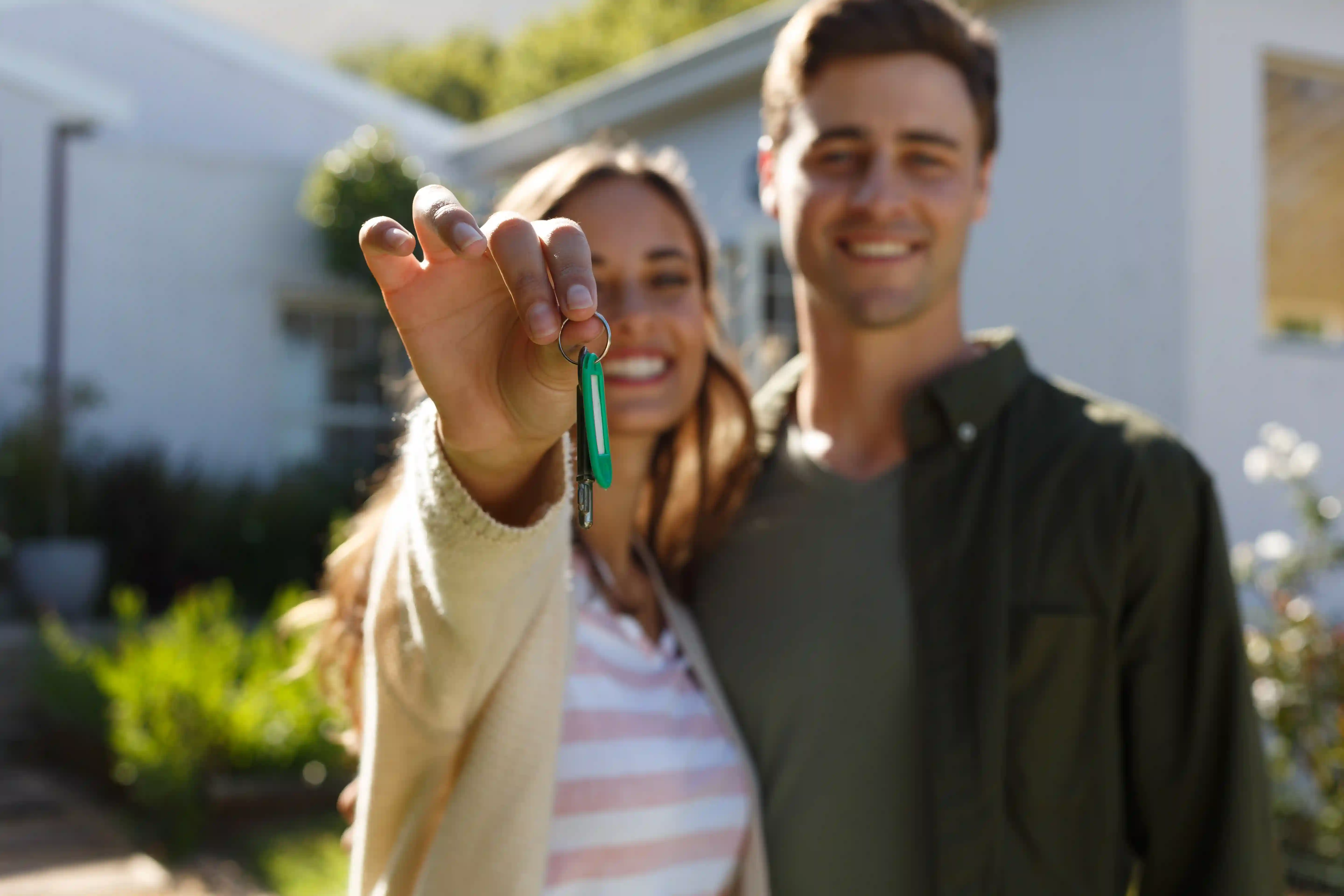 Young couple holding up keys in front of their new home