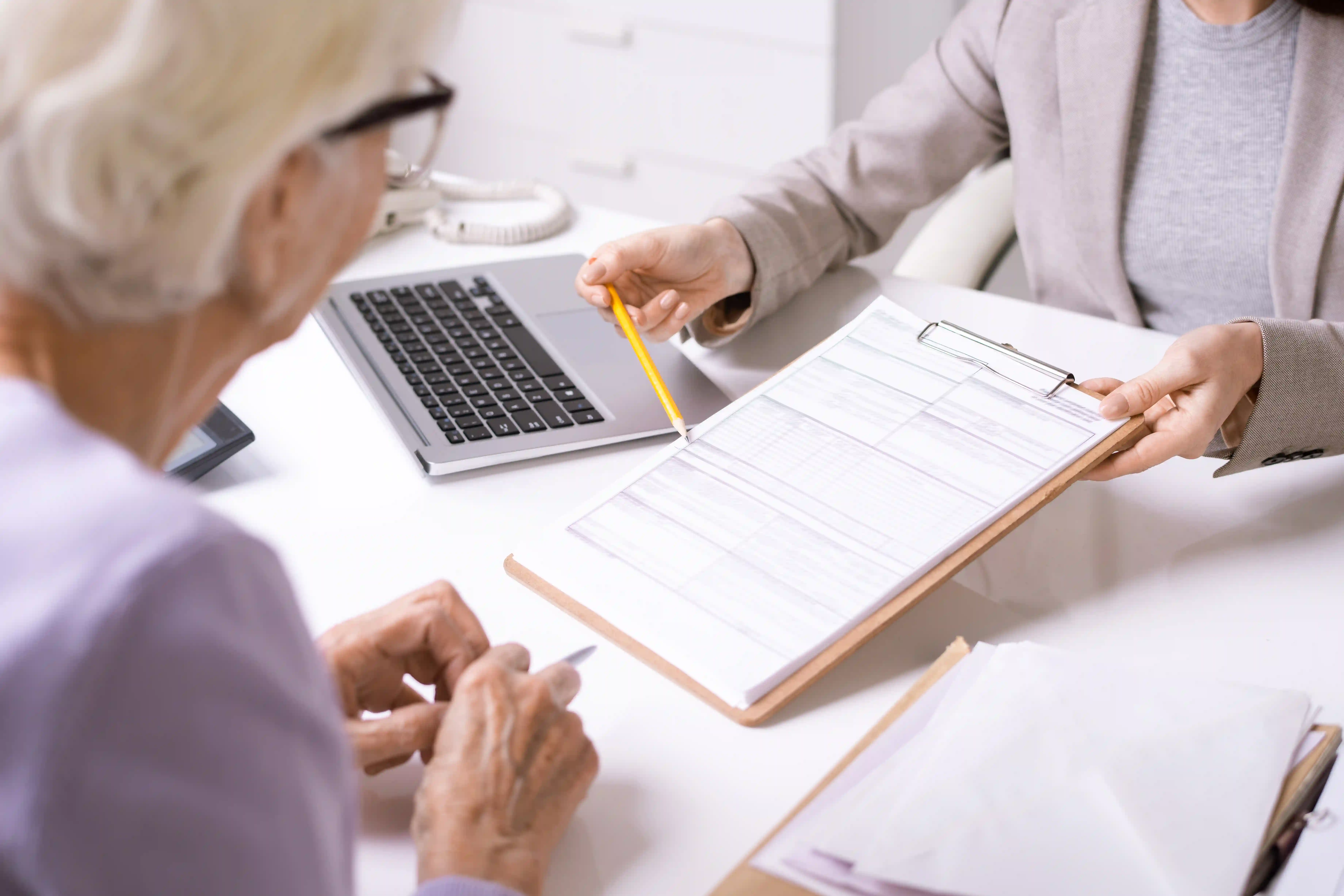Elderly lady being presented with a clipboard of paperwork to sign