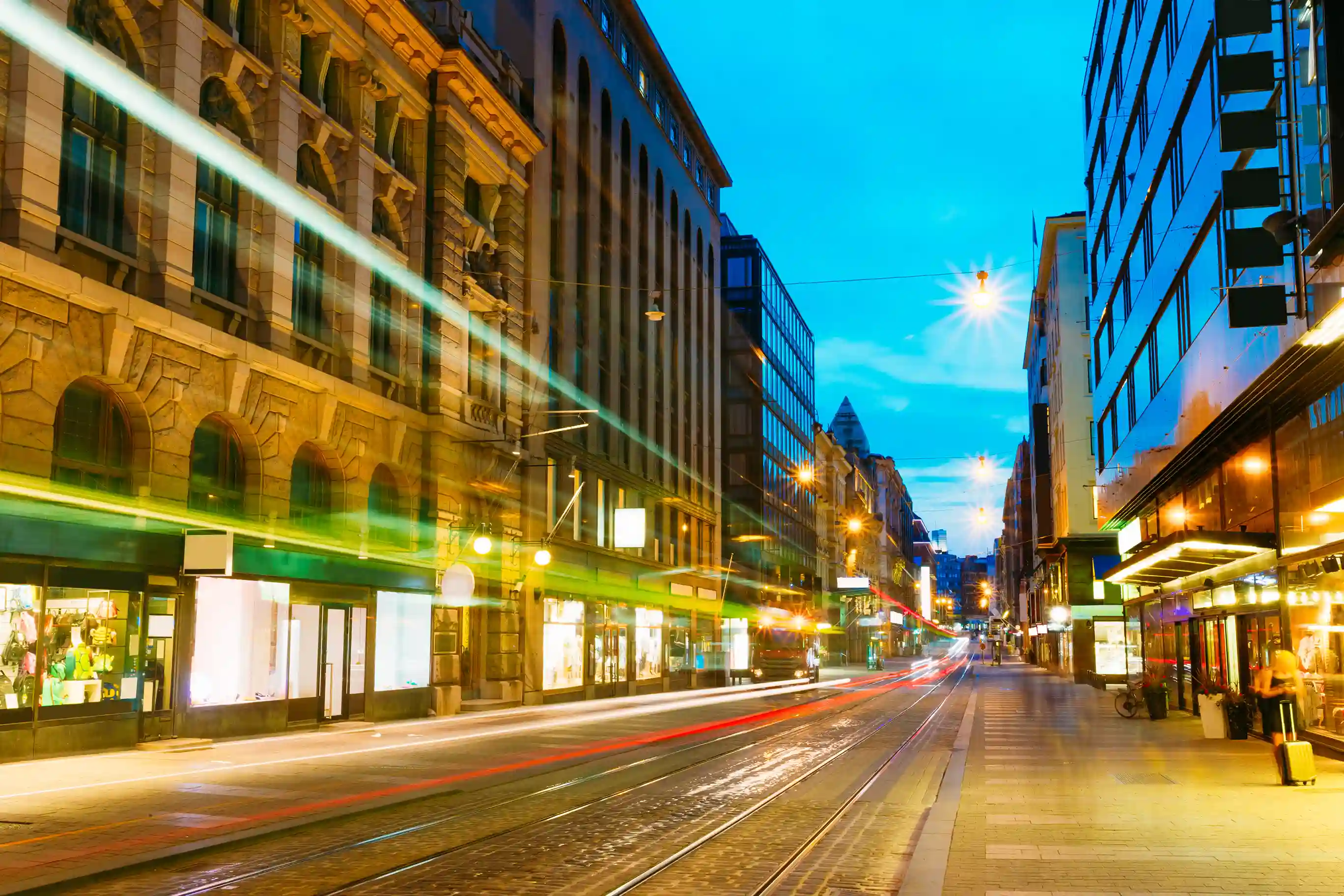 City streets at night with light trails from cars and trams passing by