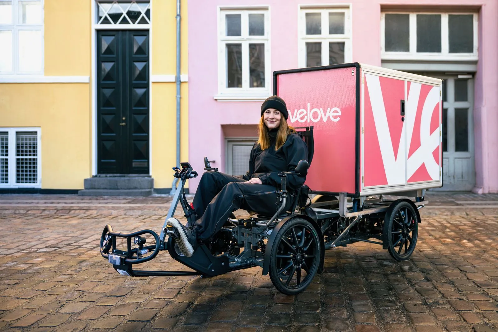 Velove-cykelbud med en eldriven lastcykel på en kullerstensgata.