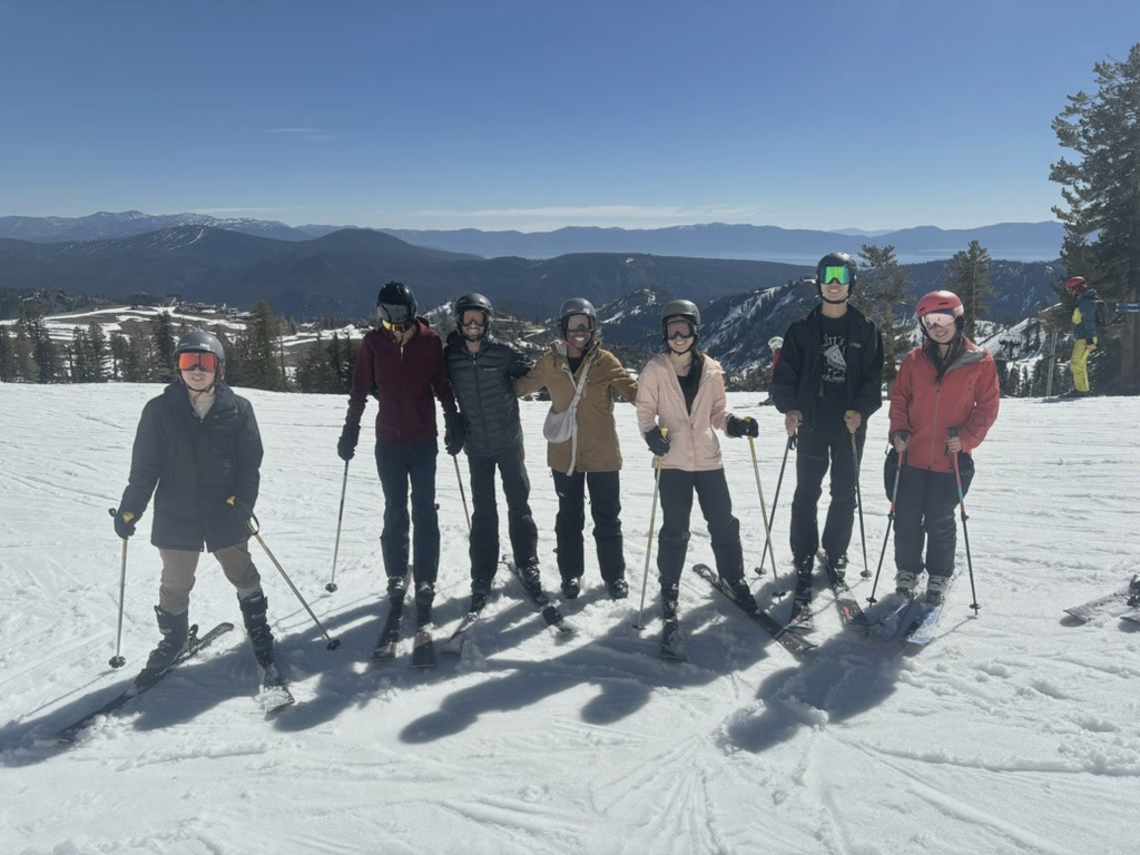 Seven Phonic team members standing with skis on a snowy mountain.