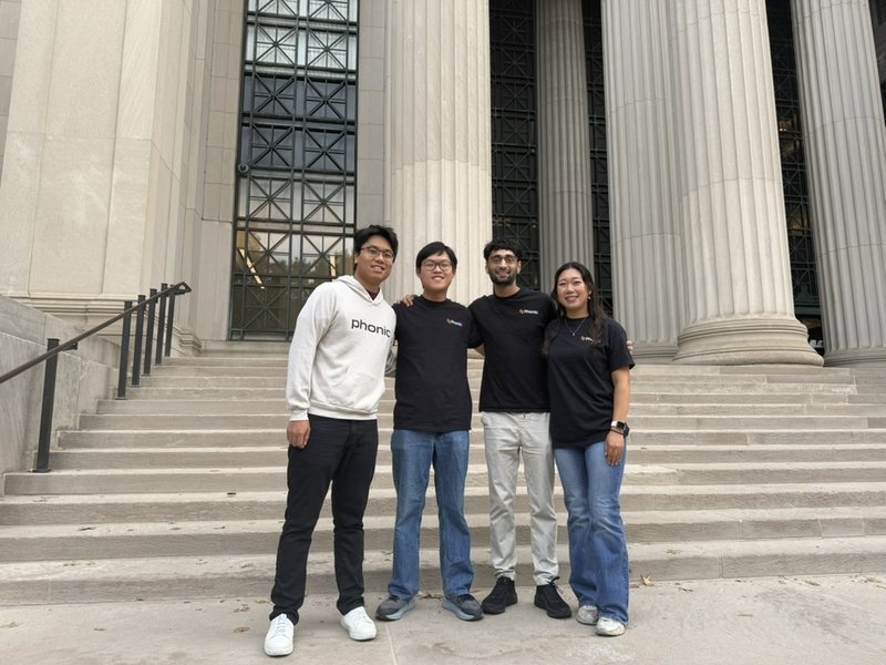 Four members of the Phonic team in Phonic shirts on the steps of MIT's Building 10
