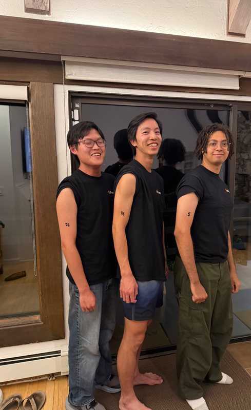 Three Phonic teammates showing off matching Phonic logo tattoos