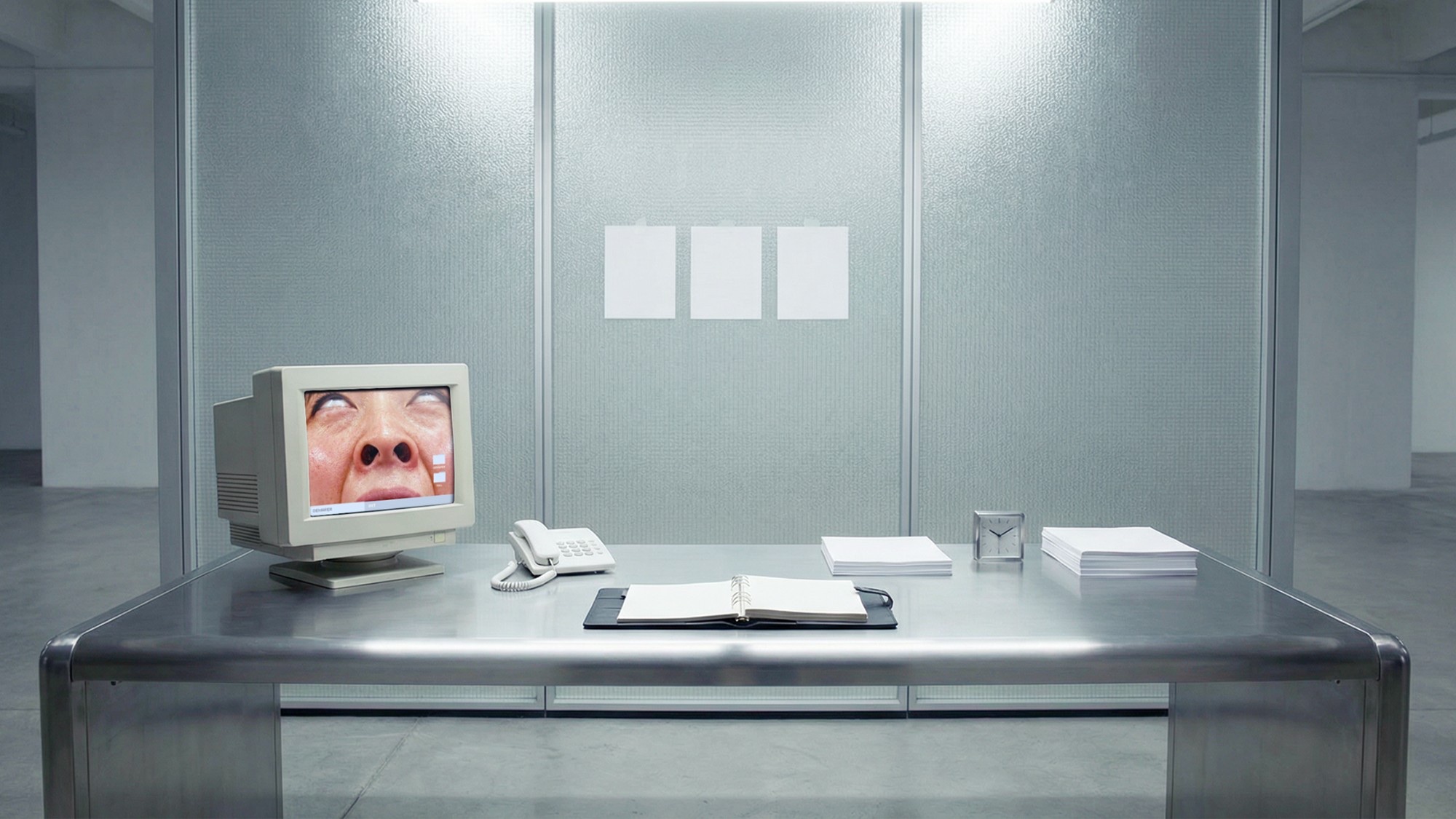 A face pressed inside an old computer screen on a steel desk