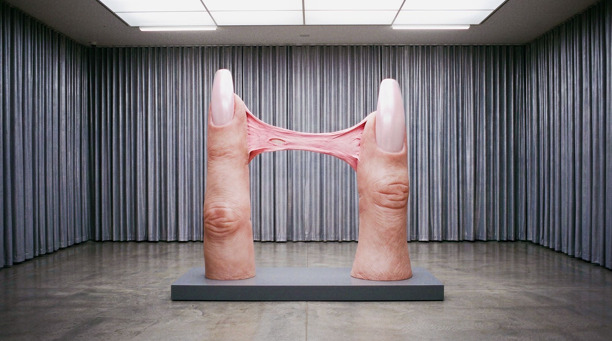Sculpture of two giant fingers joined by pink gum in a gallery