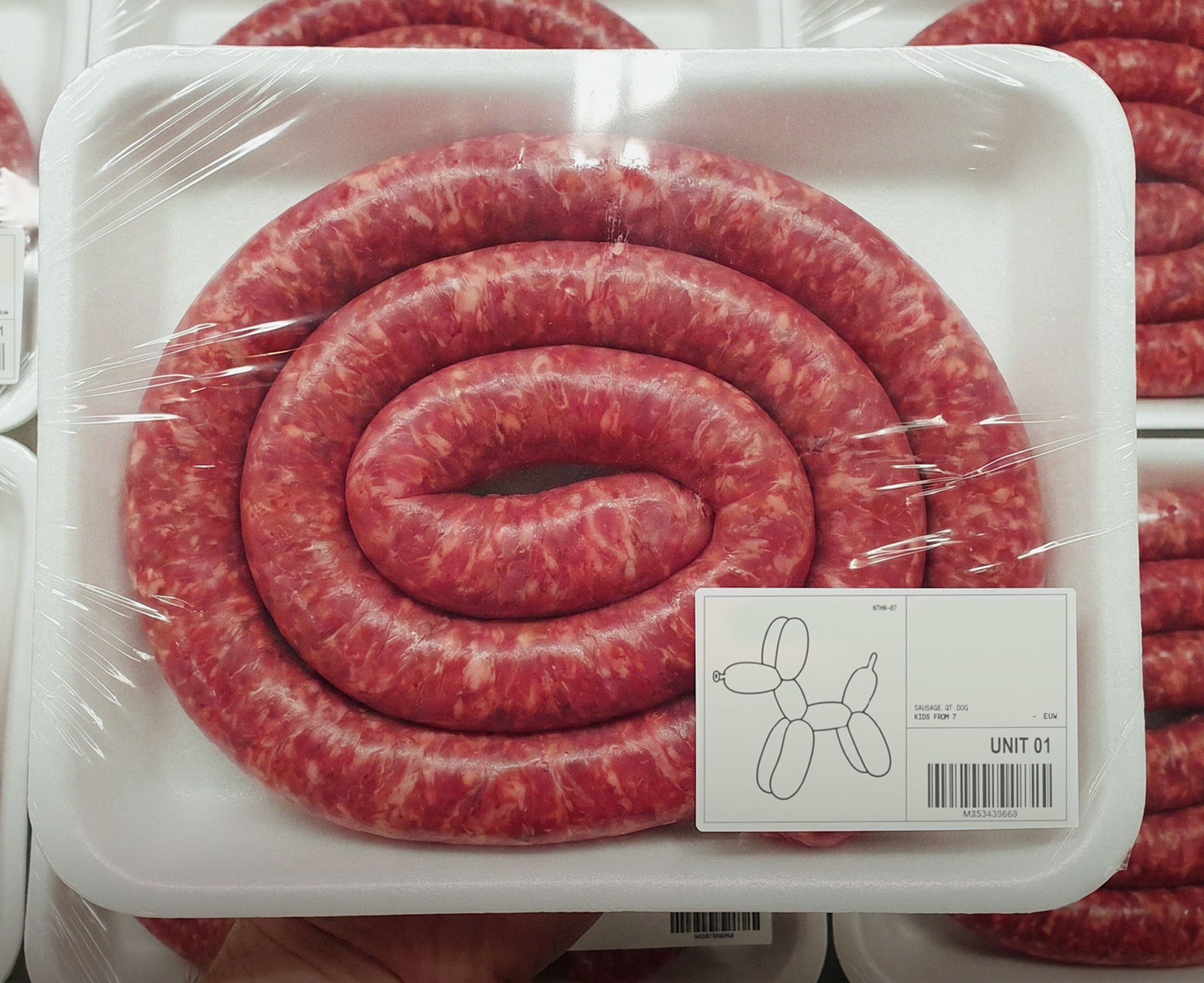 Coiled sausage in a supermarket tray with a balloon dog label
