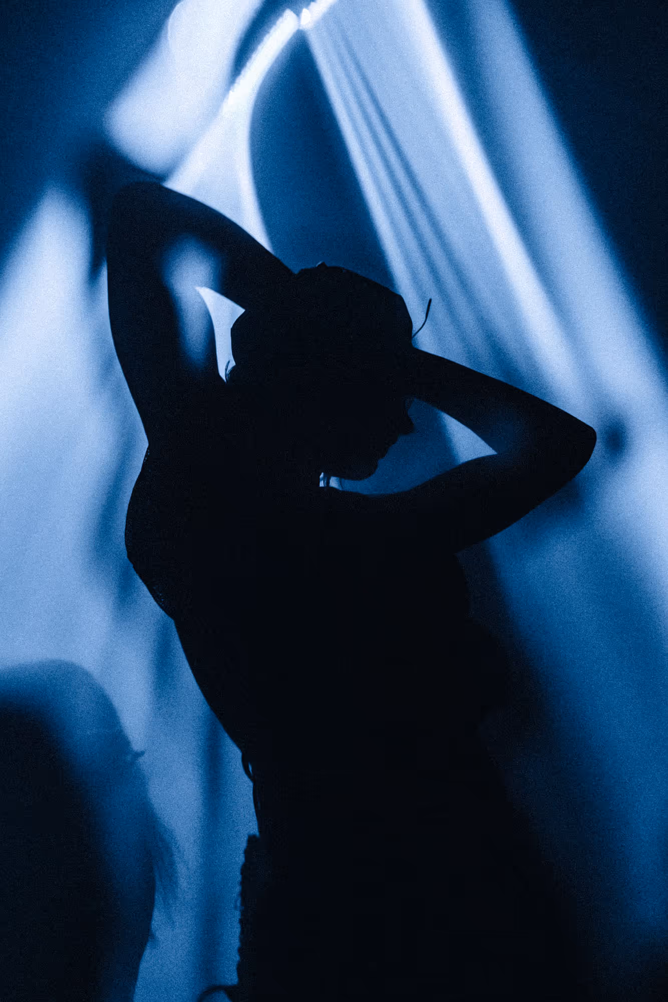 Silhouette of a person raising their arms against a blue light and smoke background.