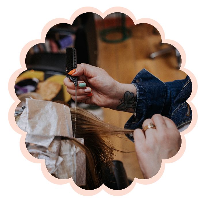 Hands sectioning hair with a comb and foil during a hair coloring process at a salon.