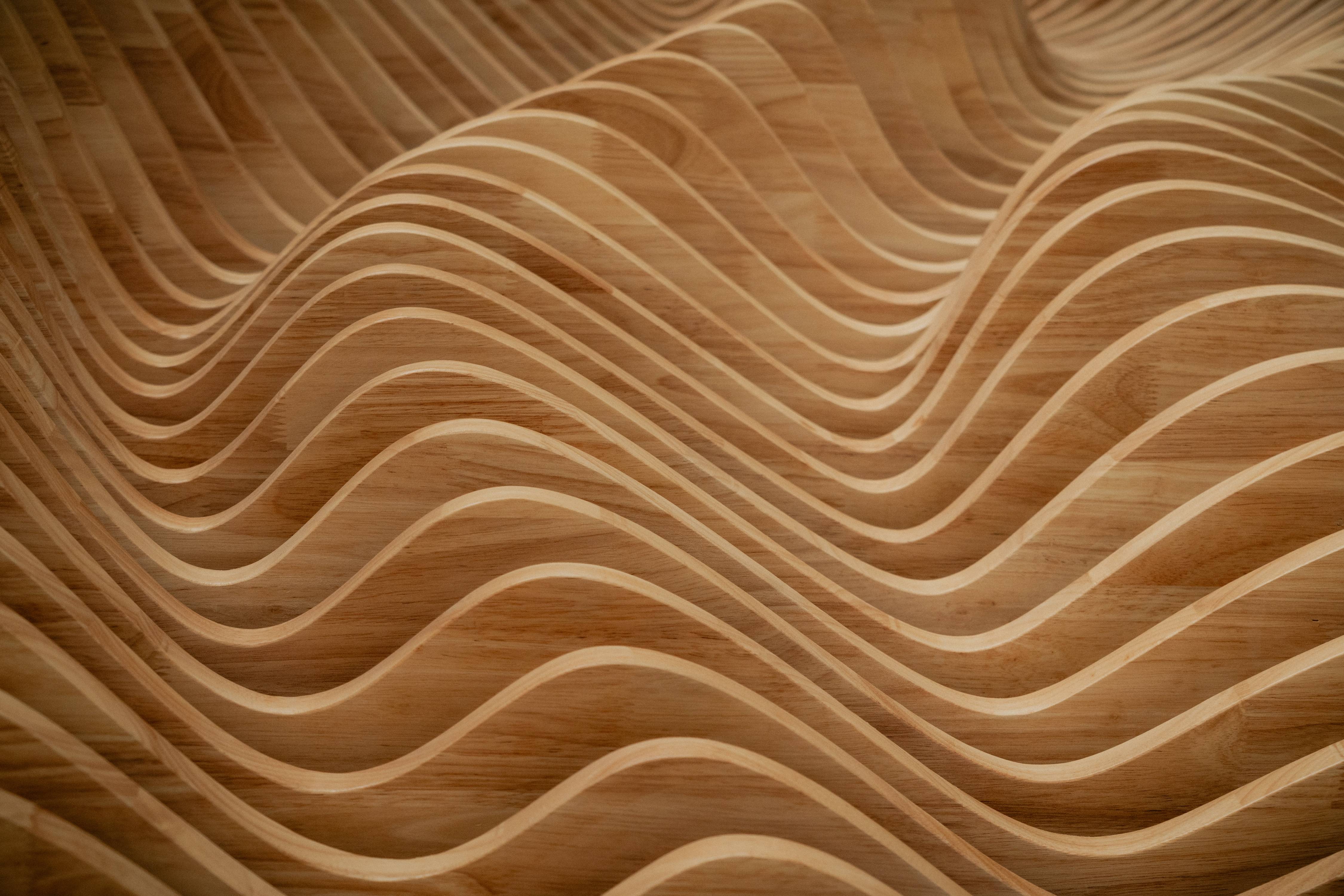 Close-up of layered wood carved into smooth, flowing wave-like patterns.