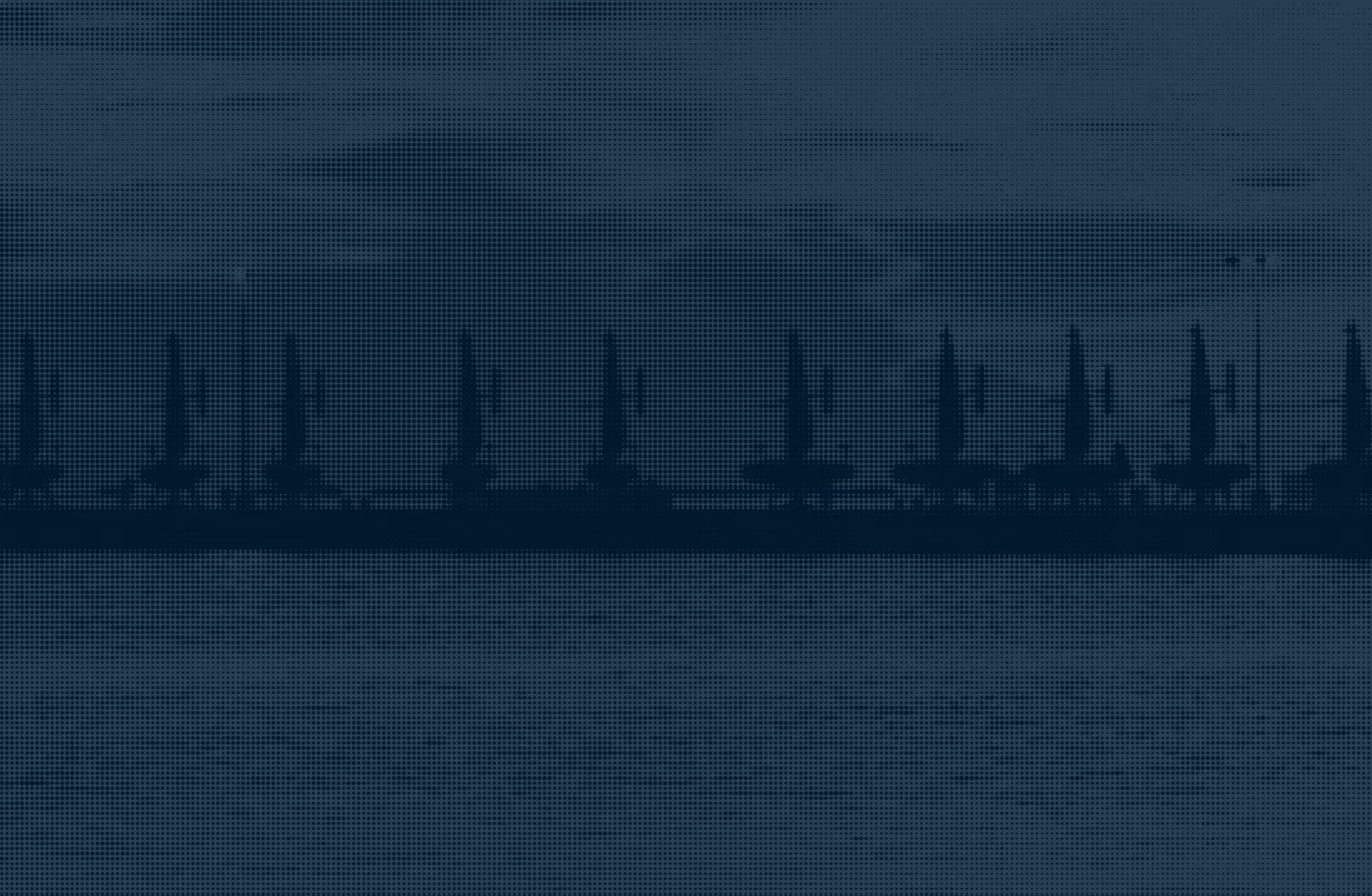 Dark silhouette of Saildrones on a marina with water in foreground at dusk.