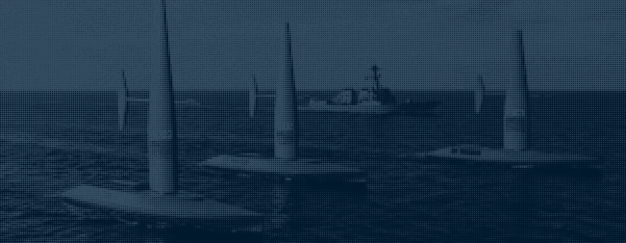 Several Saildrones in the ocean with a ship in the background.