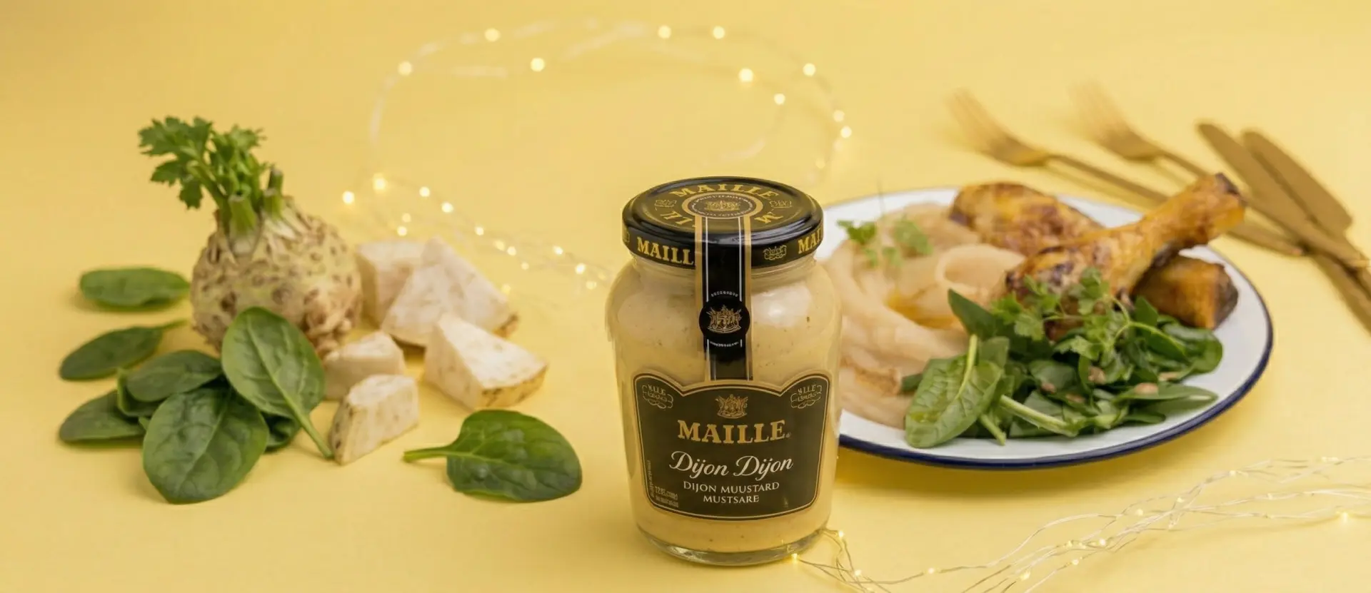 Pot de moutarde de Dijon Maille entouré d'épinards frais, céleri-rave, et assiette avec viande rôtie, oignons et légumes verts.