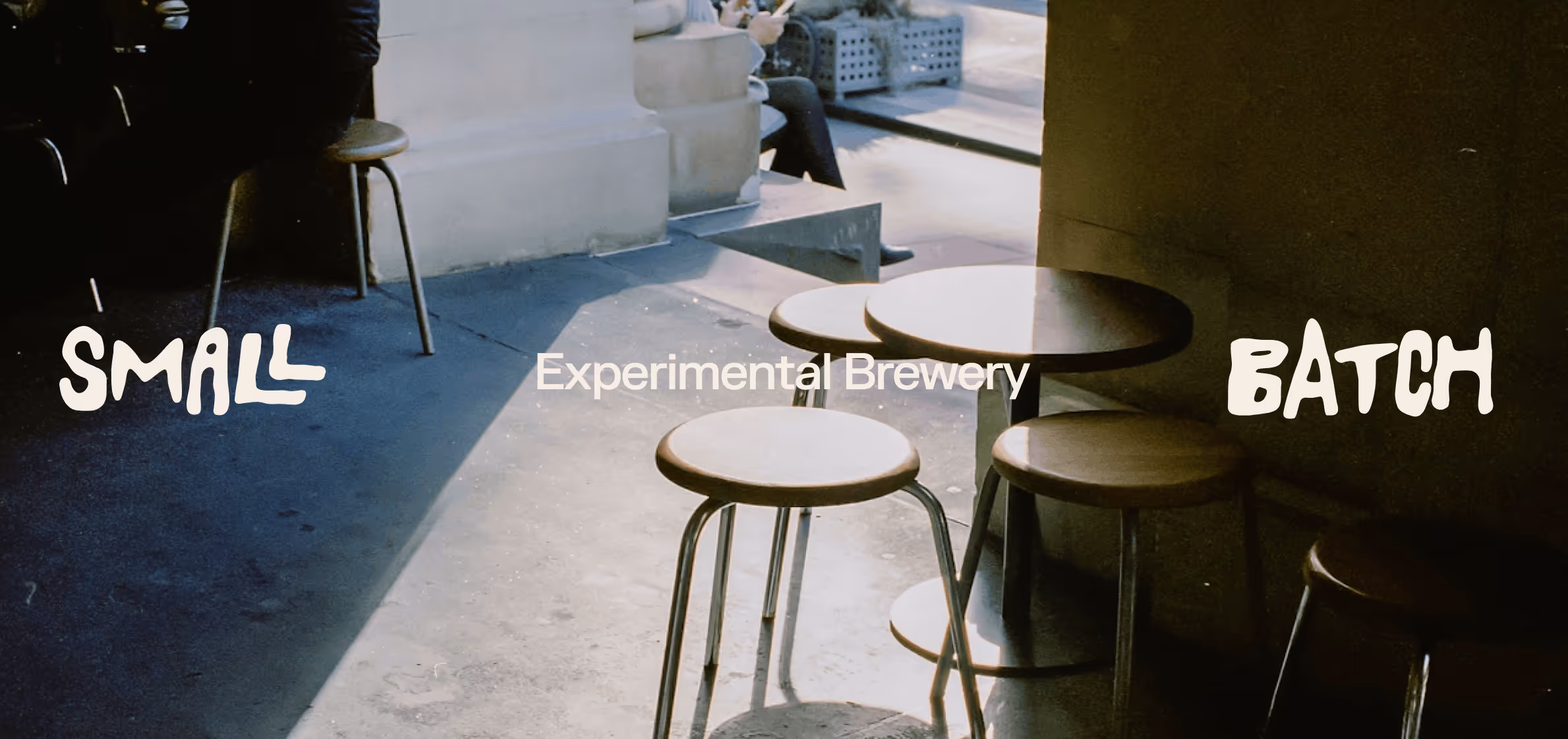 Small round tables and stools with sunlight casting shadows in a brewery seating area.