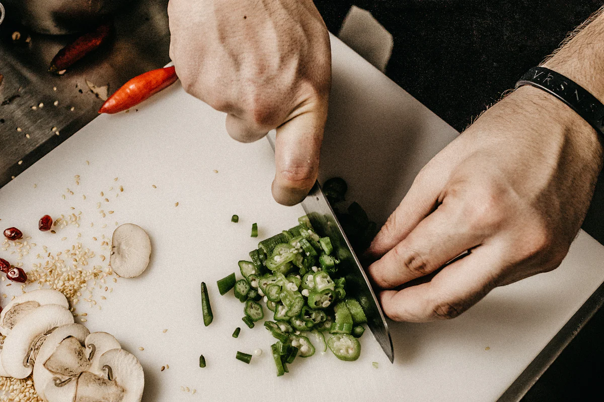 Hands slicing okra on a cutting board, framed as recorded footage