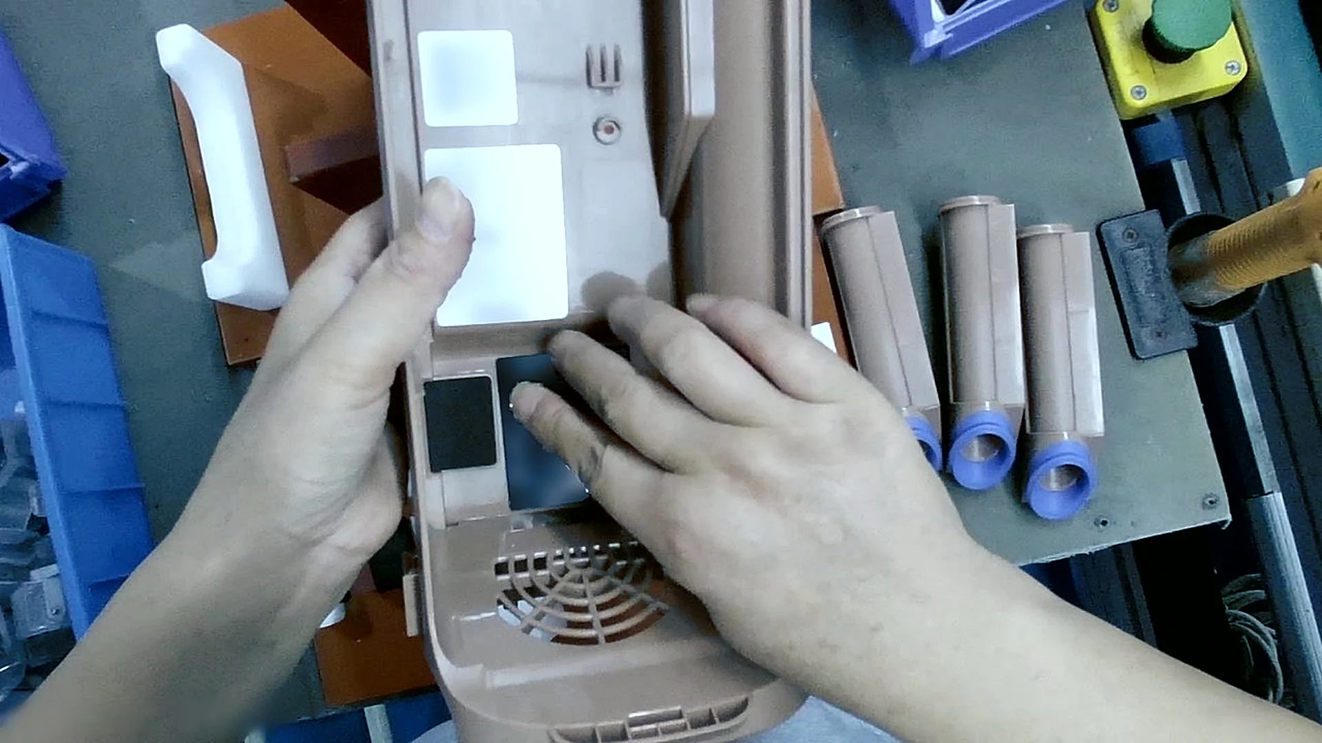Golden-set clip G31: both hands hold an appliance housing while the right fingertips smooth down a black pad at a factory station