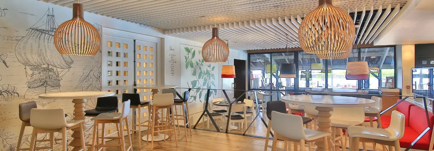 Espace restaurant La Route des Épices à l’hôtel Résidence & Spa Mahogany avec luminaires design et tables conviviales, le Gosier Guadeloupe.