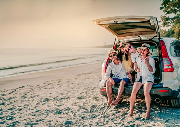 Tagesausklang auf Guadeloupe: Eltern und Kinder entspannen sich im Kofferraum ihres Fahrzeugs am Sandstrand, ganz in der Nähe des Mahogany Hôtel Résidence & Spa.