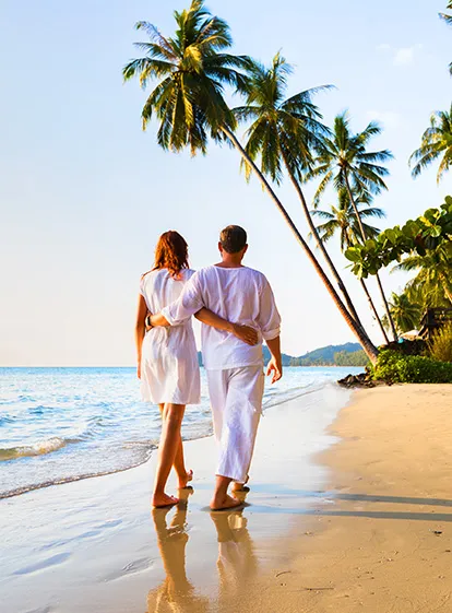 Couple on a white sand tropical beach facing the turquoise Caribbean waters at the Mahogany Hotel Residence & Spa, Le Gosier, Guadeloupe.