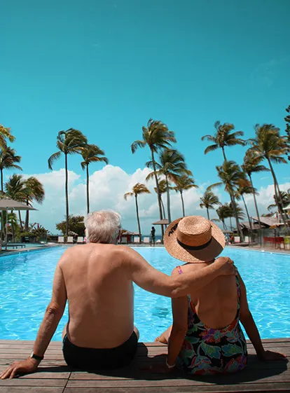 Pareja de personas mayores disfrutando de un momento de tranquilidad junto a la piscina en el hotel Résidence & Spa Mahogany, Le Gosier, Guadalupe.