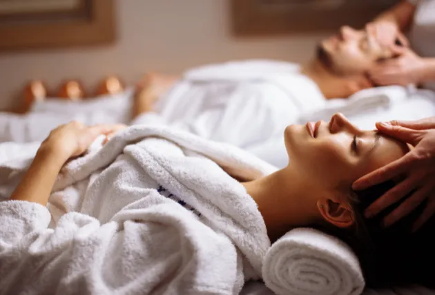Entspannte Frau und entspannter Mann liegen auf Massageliegen und erhalten eine Gesichtsbehandlung im Spa-Bereich des Mahogany Hôtel Résidence & Spa, Le Gosier, Guadeloupe.