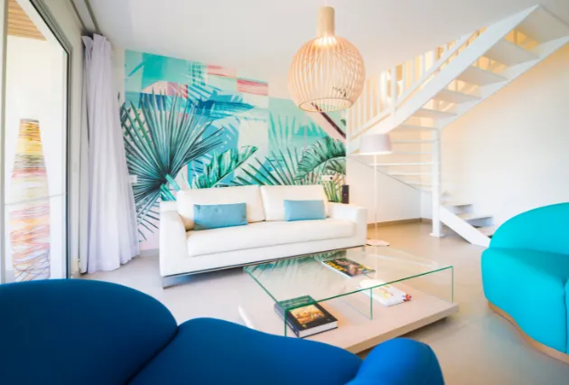 Salon en duplex avec canapé crème, fauteuils colorés et suspension en bois. Mahogany Hôtel, Guadeloupe.