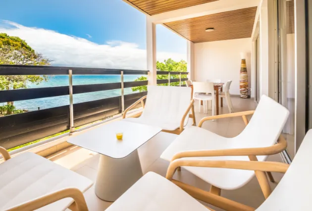 Balcon avec chaises longues blanches, table basse et vue sur la mer. Mahogany Hôtel, Guadeloupe.