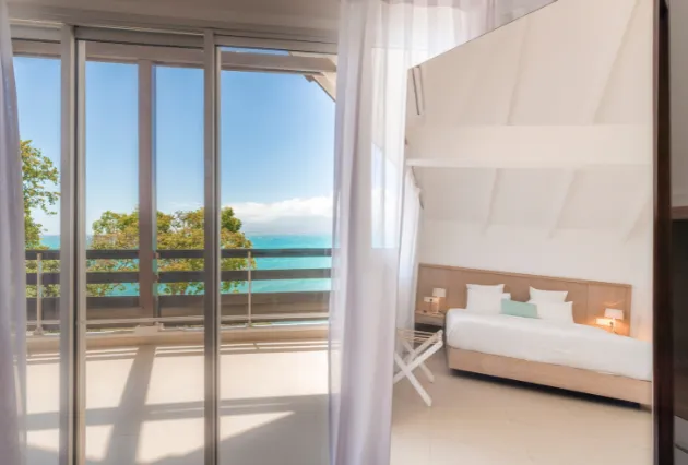 Vue composite : à gauche un balcon avec vue mer, à droite une chambre avec grand lit. Mahogany Hôtel, Guadeloupe.