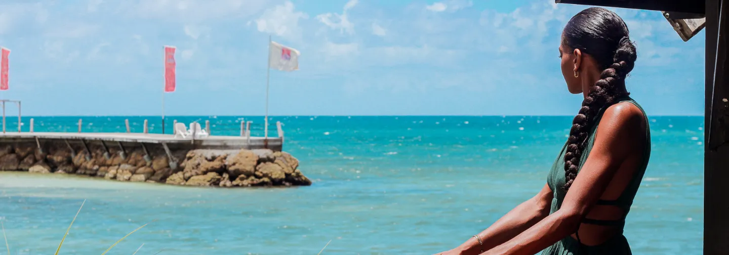 Rear view of a woman looking out at the Caribbean Sea from a terrace, Mahogany Hotel, Le Gosier, Guadeloupe.