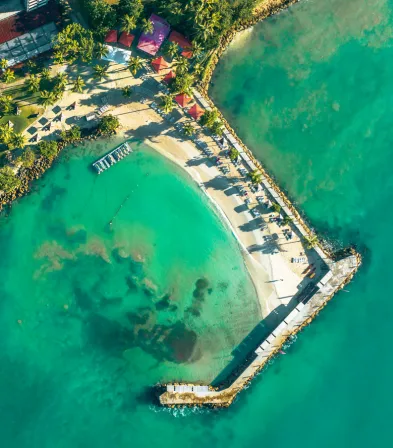 Vista aérea de la piscina rodeada de jardines tropicales en el Mahogany Hôtel Résidence & Spa, en Le Gosier, Guadalupe.