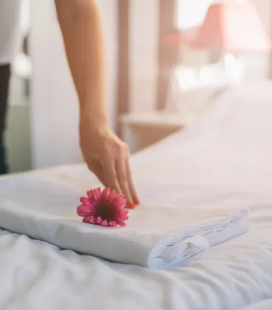 Detailaufnahme eines liebevoll vorbereiteten Hotelzimmers mit einer Blume auf dem Bett im Mahogany Hôtel Résidence & Spa, Guadeloupe.