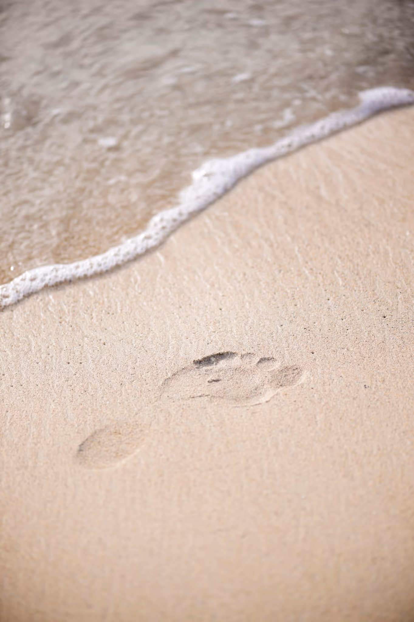 Empreinte de pied unique sur le sable humide en bord de mer à Mahogany Hôtel Résidence & Spa, Pointe de la Verdure, 97190 Le Gosier, Guadeloupe.