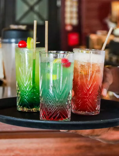 Gros plan sur trois cocktails colorés servis sur un plateau noir, Mahogany Hôtel Résidence & Spa, Le Gosier.