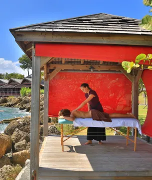 Séance de massage en plein air dans une cabane en bois au bord de l'eau à Mahogany Hôtel Résidence & Spa, Le Gosier, Guadeloupe.