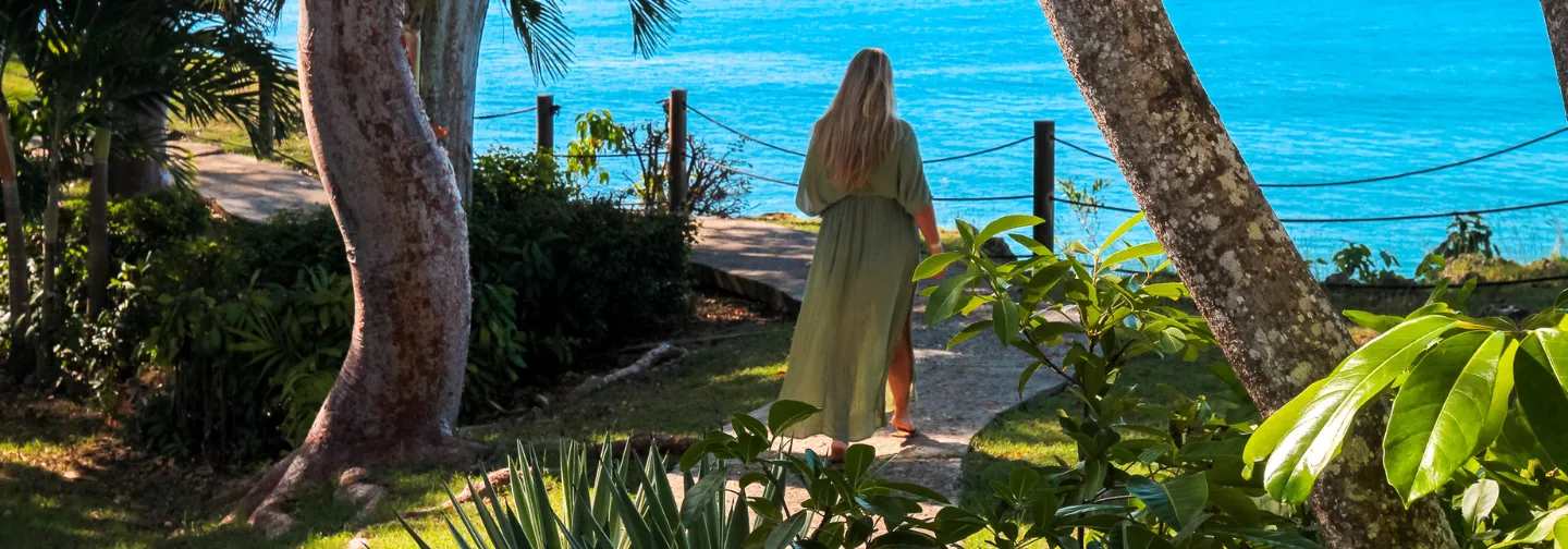 Küstenpfad des Mahogany Hôtel Résidence & Spa in Le Gosier (Guadeloupe) mit einer Person, die am Wasser spazieren geht.