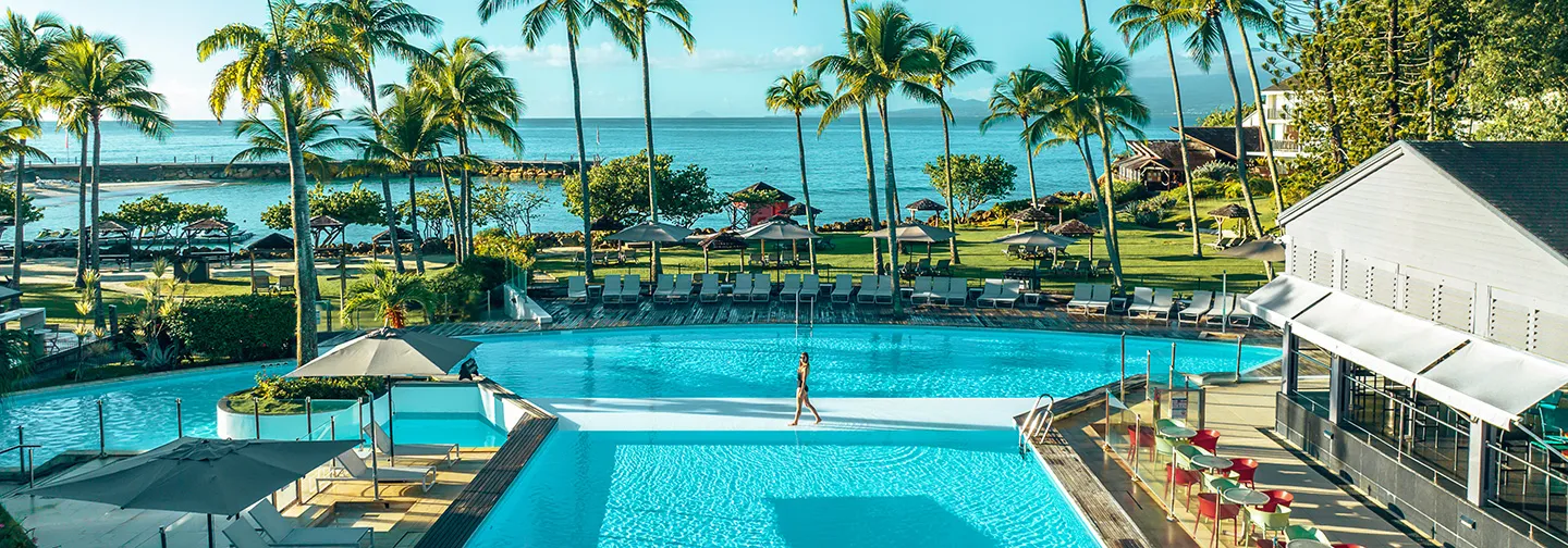 Vue panoramique sur la piscine, le jardin tropical et l'océan au Mahogany Hôtel Résidence & Spa