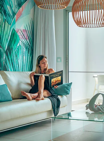 Femme lisant un livre dans le salon moderne du Mahogany Hôtel Résidence & Spa pour une offre solo en Guadeloupe