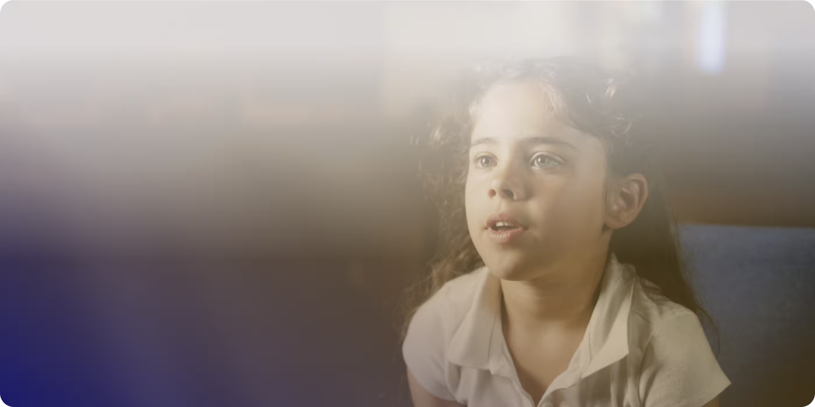 Young girl with curly hair and white shirt looking forward with a thoughtful expression.