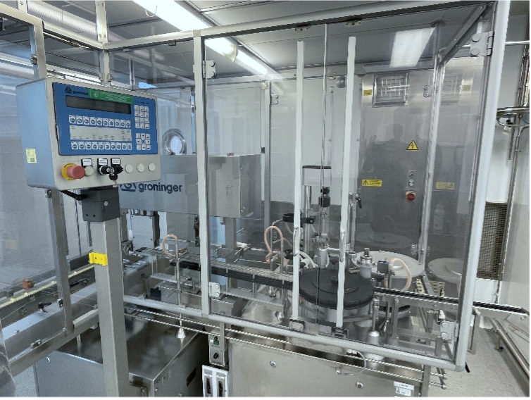 Groninger syringe filling machine with control panel and rotary table behind clear safety guarding in a cleanroom